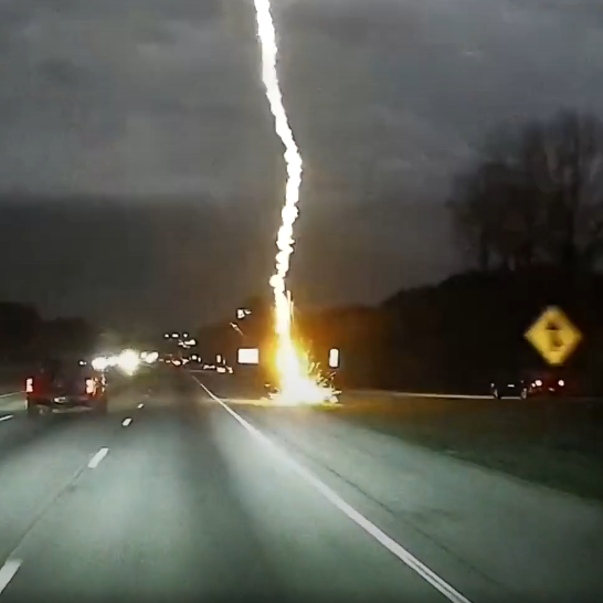 Lightning striking near a highway during night time.